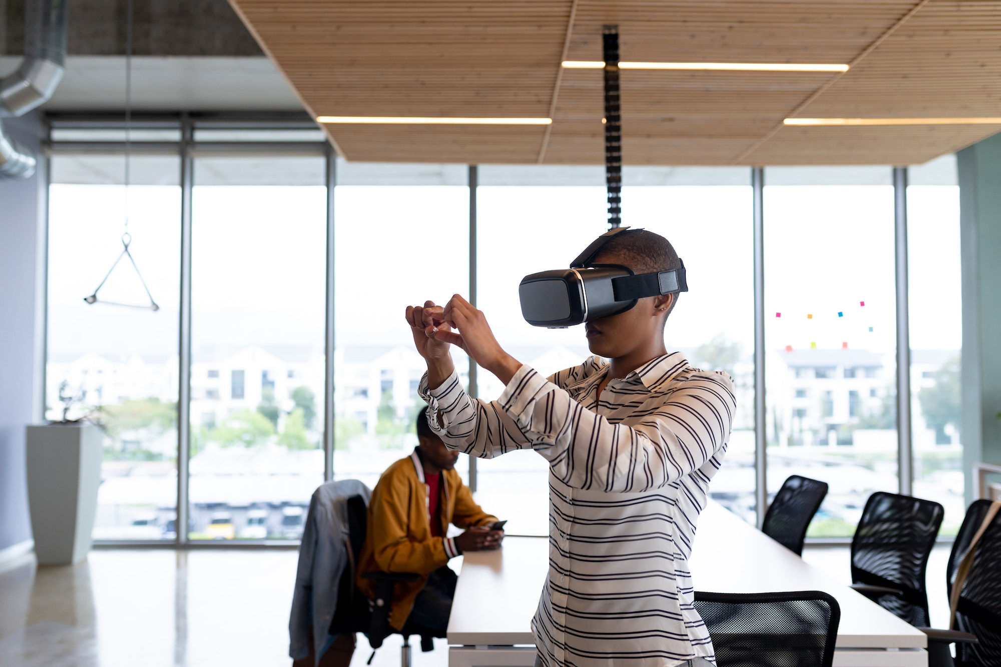 Creative businesswoman in casual gesturing while using virtual reality headset in office