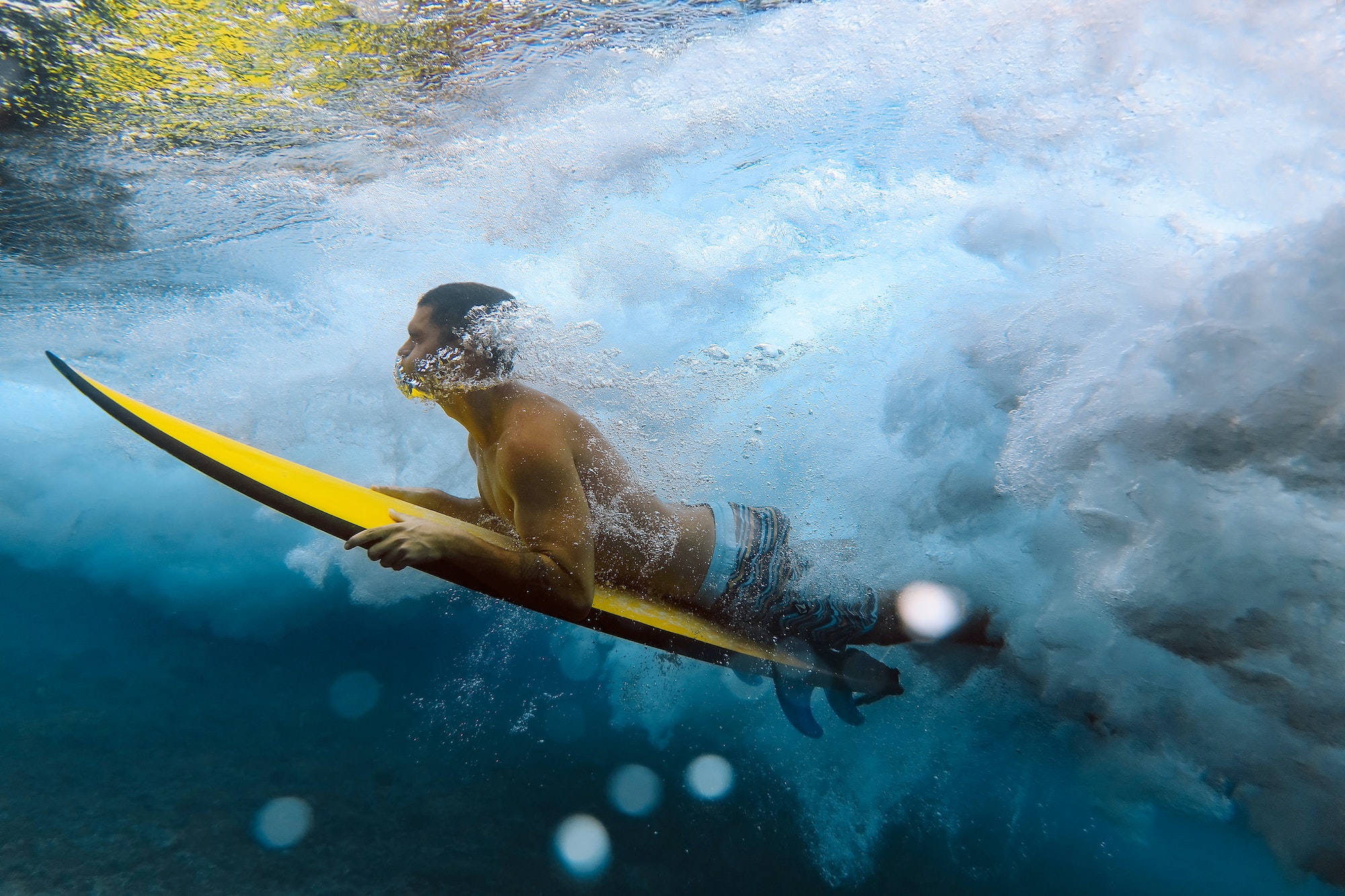 Shirtless male surfer diving in sea at Maldives